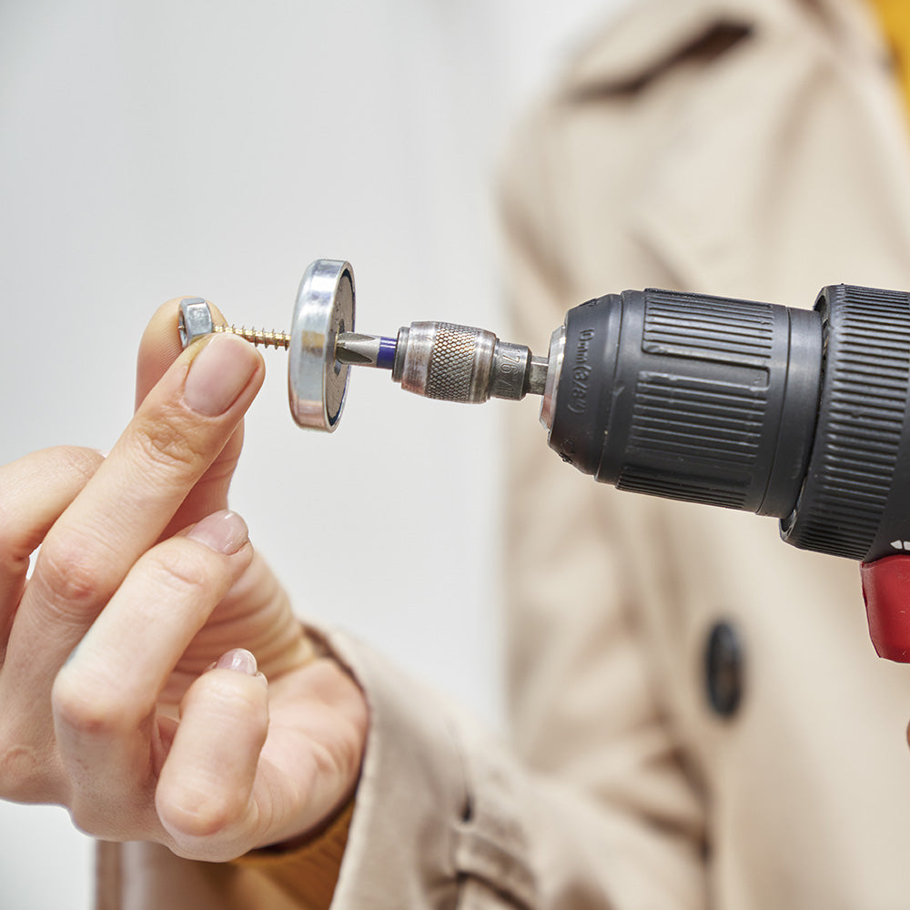 Close-up of hand installing magnetic mounting hardware for a modular whiteboard — showing easy, tool-friendly setup with precision parts.